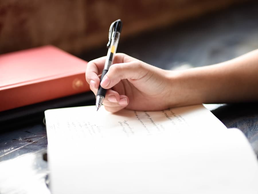 Hand writing an entry in a notebook with a pen